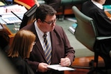 Liberal National Party MP George Christensen writes on a pad of paper in the house of representatives