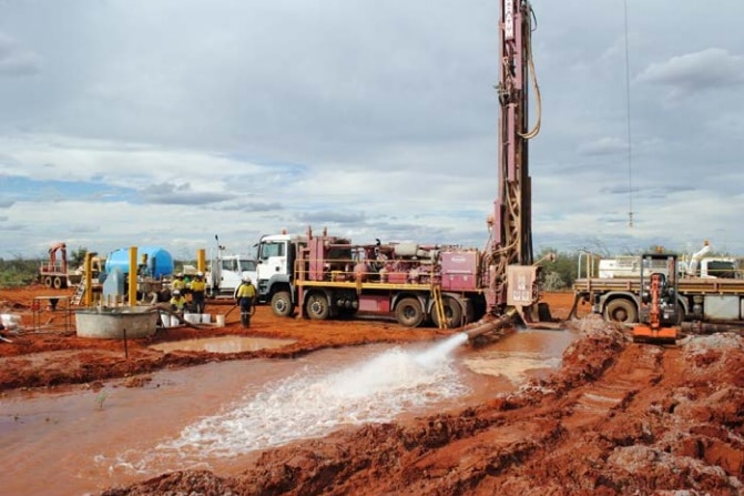 A large water bore rig in action on a Martian-looking landscape.