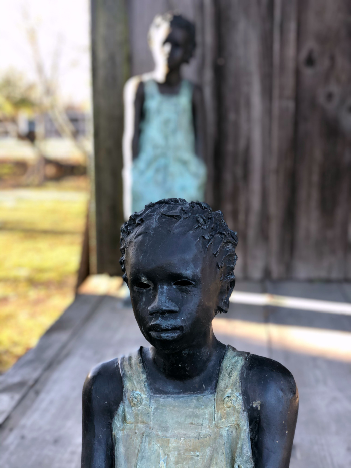 A statue of a child in overalls at Whitney Plantation.