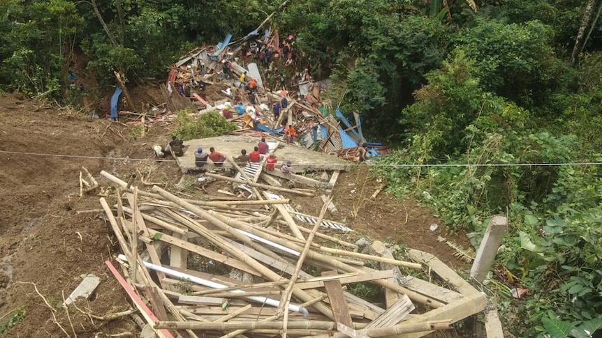 A scene of a mud landslide with broken wood and people at the bottom