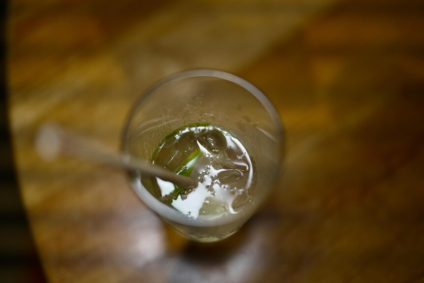 A clear drink with some ice and a lime wedge in it. 