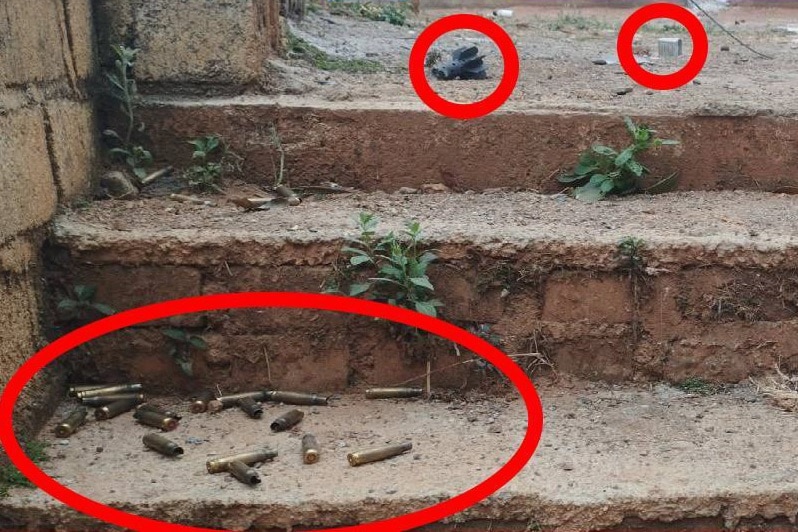 A red line is circled around bullets, a mortar round, and bullet packaging found sitting on outside steps in a village.