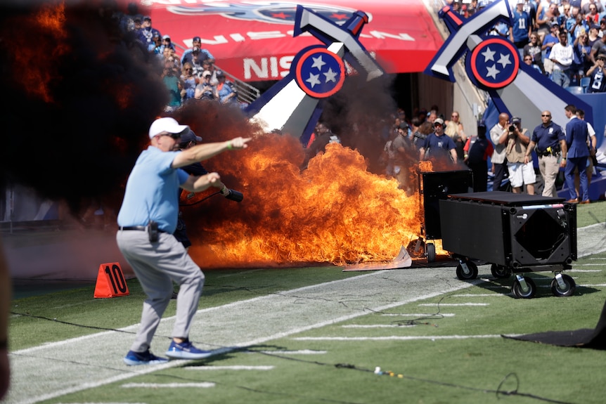 A man points as a fire burns behind him