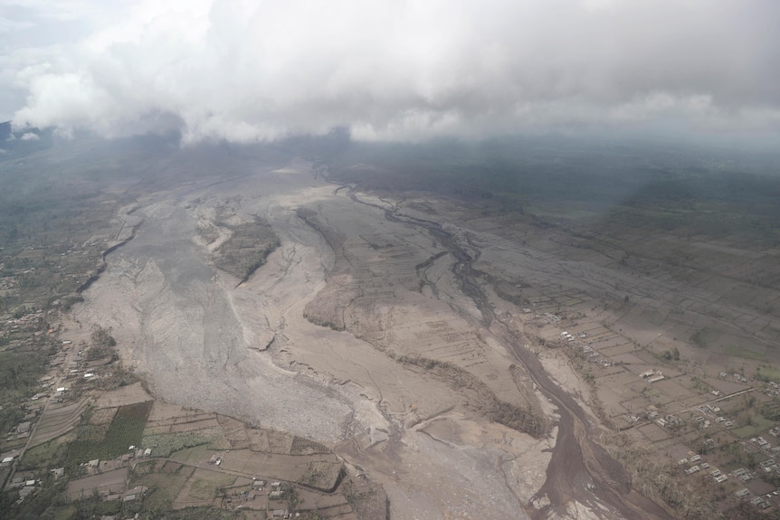 An aerial shot shows the path of lava and ash stretching like a river into the distance after a volcanic eruption.