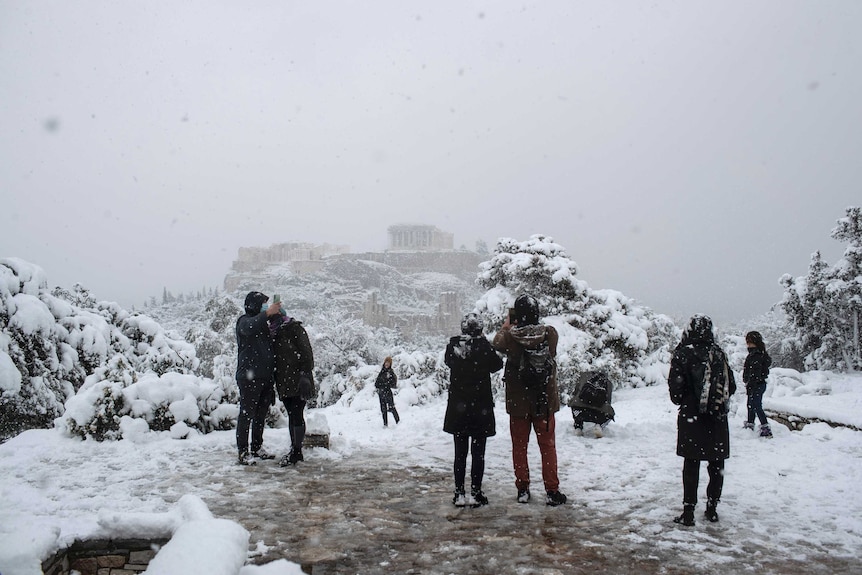 People take pictures in front of the ancient Acropolis hill.