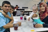Mamutjan Abdurehim, far left, sits at a table in a restaurant his wife and two children.