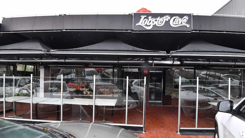 Cars parked outside the Melbourne seafood restaurant Lobster Cave on a drizzly, grey day.