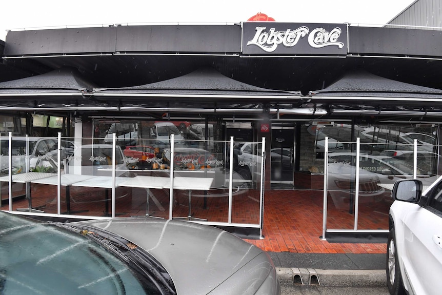 Cars parked outside the Melbourne seafood restaurant Lobster Cave on a drizzly, grey day