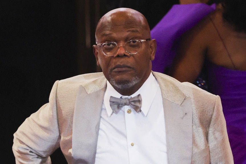 Samuel L. Jackson with his hand on his hip dressed formally
