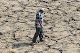 Indian man walks across dried-out lake bed