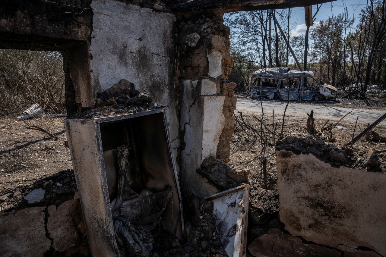 A burnt out car, seen from the interior of a destroyed building