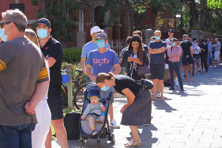 A queue of people at a COVID-19 clinic in Perth, with many wearing facemasks.