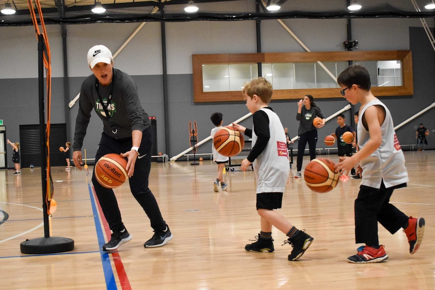 Michele Timms bounces the ball on a basketball court.