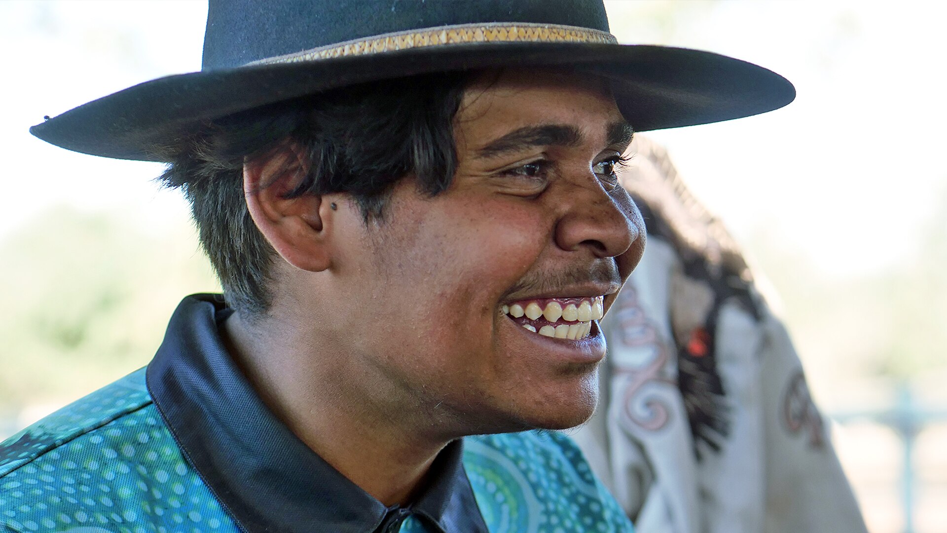 A man wearing a hat looks away from the camera