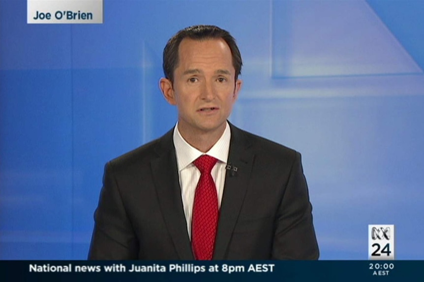 O'Brien on set with plain blue background and his name on screen in top left corner.