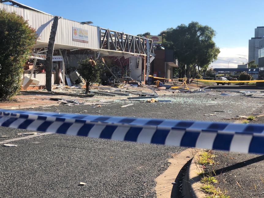 A gutted shop with debris and glass spilling out onto the road.