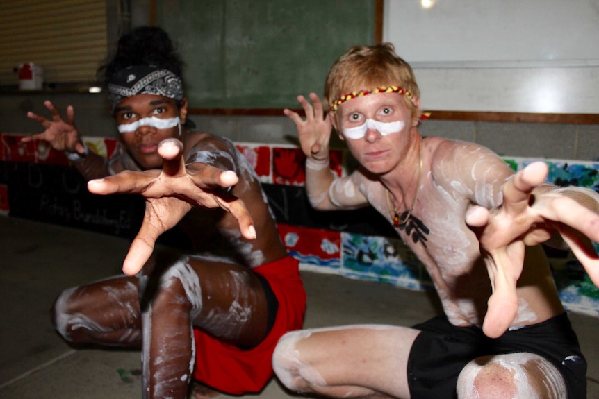 Two Aboriginal boys crouched down wearing traditional dress.