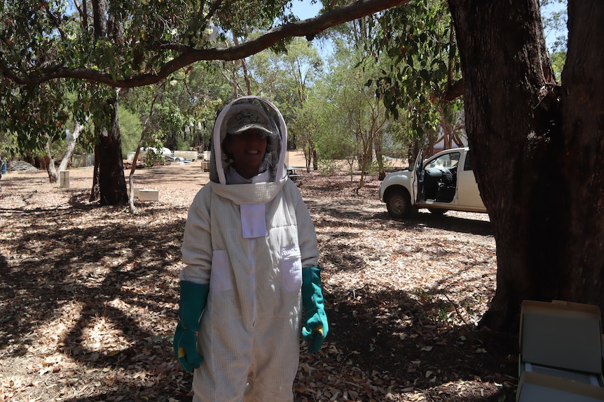 Dr Daniela Scaccabarozzi stands in a forest wearing a full beekeeping outfit