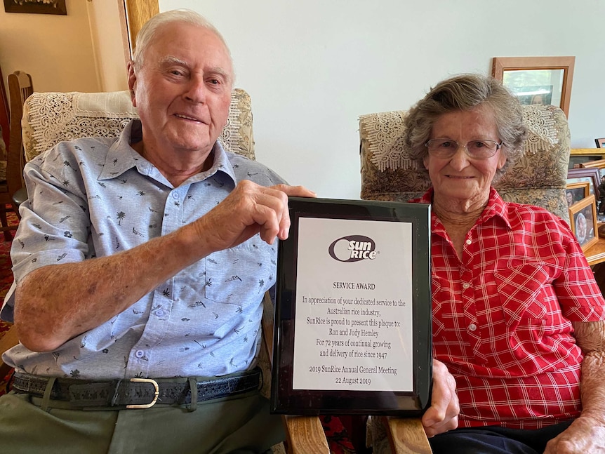 A man and woman smiling holding an award.