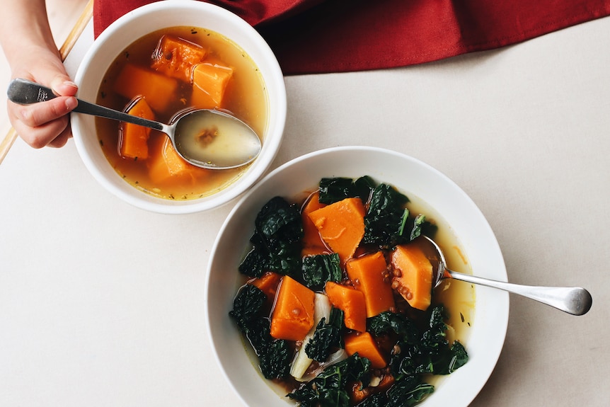 A child and adult's serving of vegetable soup with pumpkin and lentils, a one-pot family meal for winter.