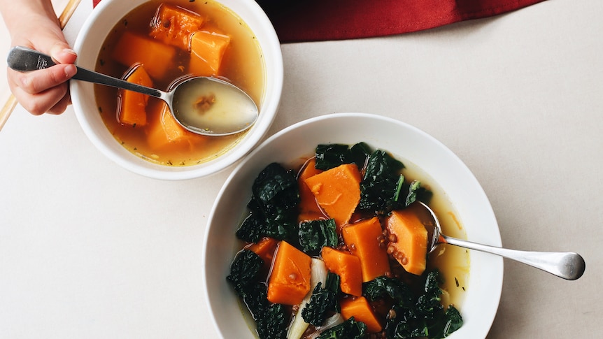 A child and adult's serving of vegetable soup with pumpkin and lentils, a one-pot family meal for winter.