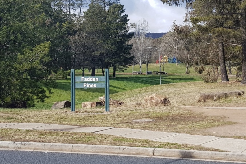 A sign for Fadden Pines in front of a park.