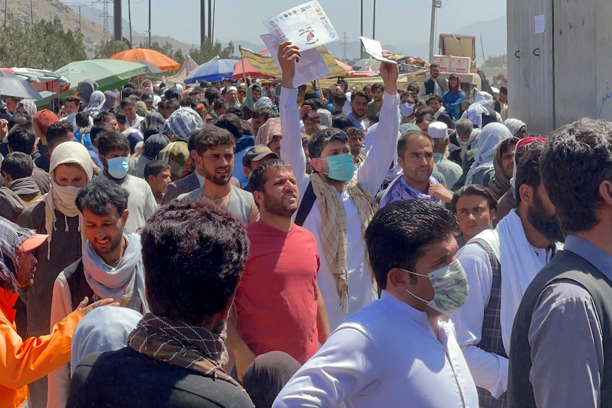 Crowds of people show their documents to US troops at Kabul airport. 