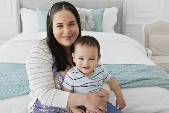 A mother cuddling her son, who is sitting on her lap.