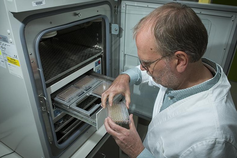 Scientist holds plastic container out of research safe in lab.