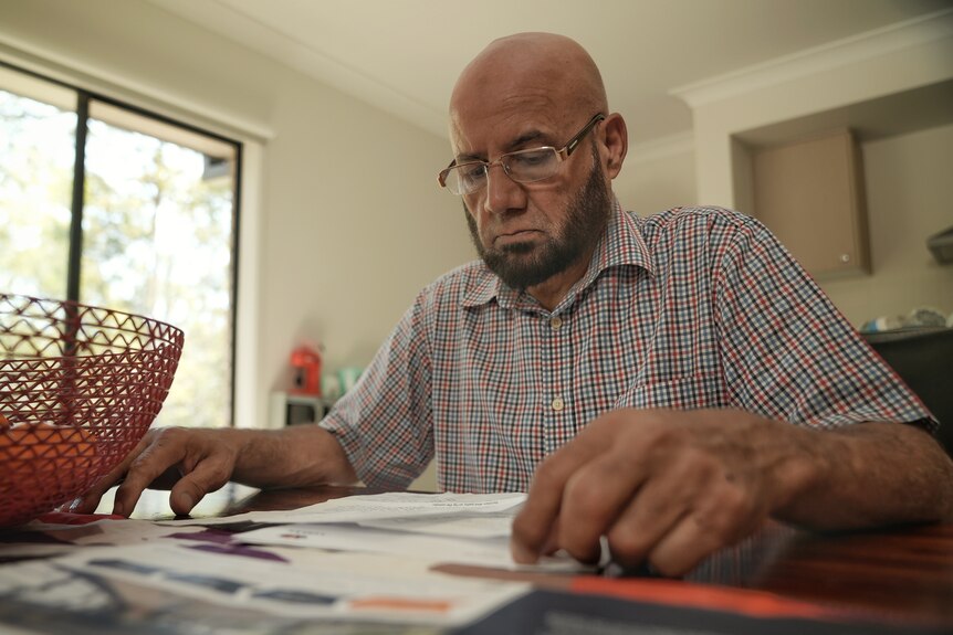 A photo of Mr Waqr sitting at a table with papers pictured in front of him. 