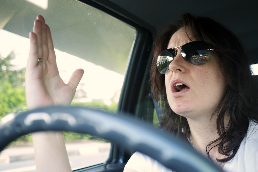 A woman gestures in anger while driving