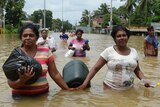 Residents walk through a flooded road in Kaduwela, Colombo