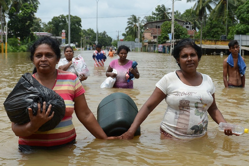 Residents walk through a flooded road in Kaduwela, Colombo