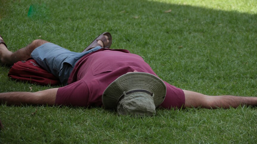 Man sleeping on the grass with arms spread wide