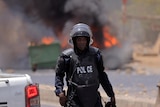 Police in riot armour in front of flames and smoke. 