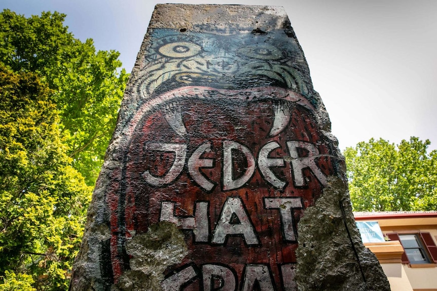 A piece of the Berlin Wall with German graffiti that translates to "everyone is powerful".