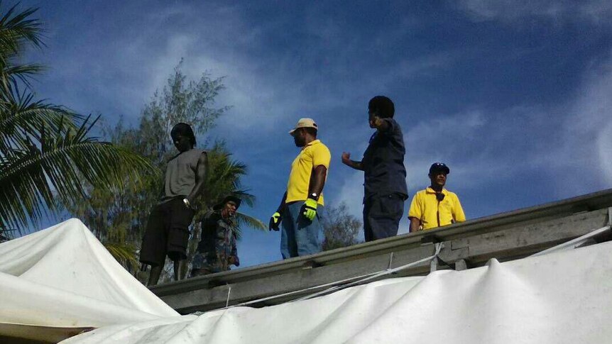 Officials stand on a roof at the Manus Island detention centre.