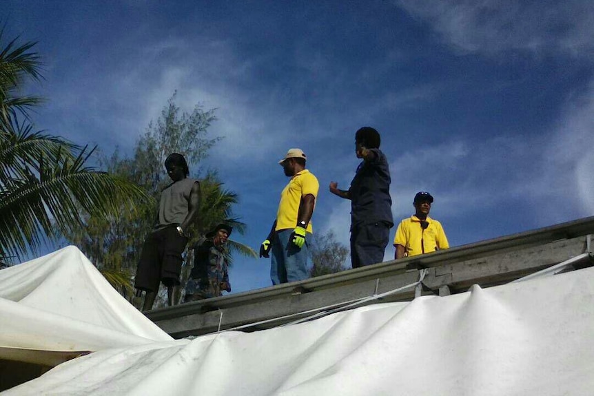 Officials stand on a roof at the Manus Island detention centre.