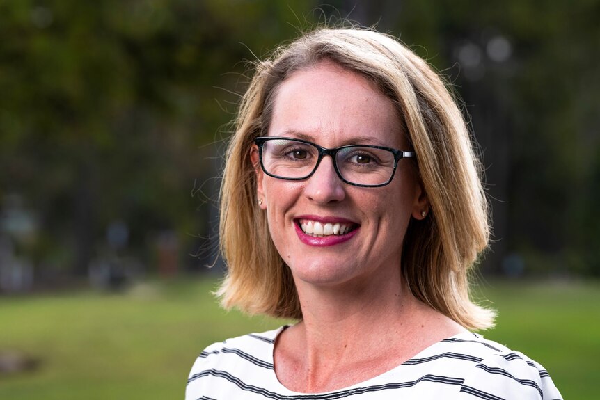 Cassandra Dittman wearing black frame glasses and smiling at camera. 