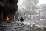 A man walks on rubble at a damaged site after an airstrike in the besieged town of Douma, Syria.