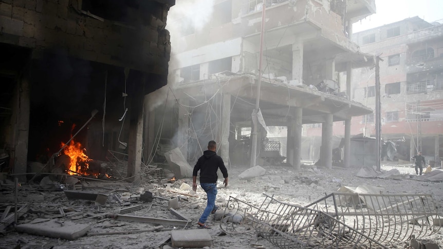 A man walks on rubble at a damaged site after an airstrike in the besieged town of Douma, Syria.