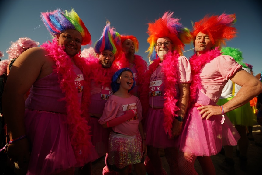 People dressed in red and Troll Doll hair smile at the camera.