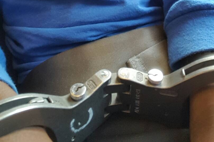 A handcuffed asylum seeker aboard the flight from Manus Island.