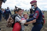A asylum seeker carrying a baby is stopped by Hungarian police