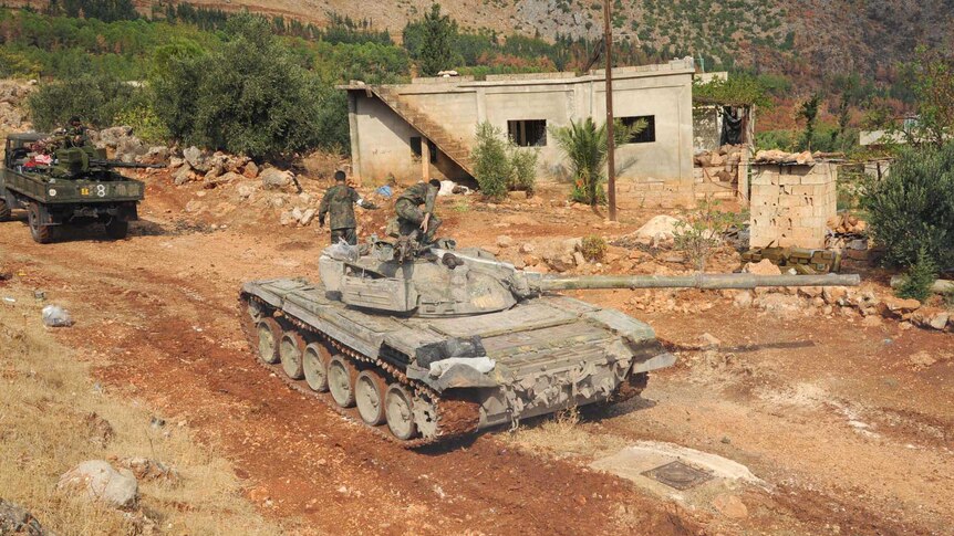 A Syrian army tank moves along a dirt road in western Syria.