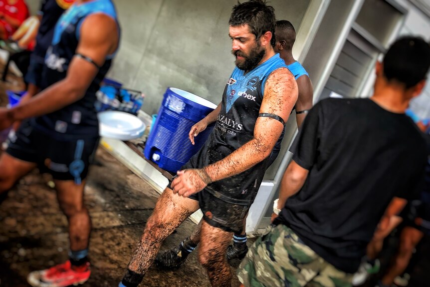 Joel Palmer covered in mud in the Buffaloes uniform.