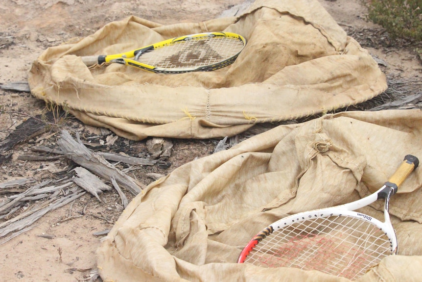 Racquets and brown bags lie on the ground
