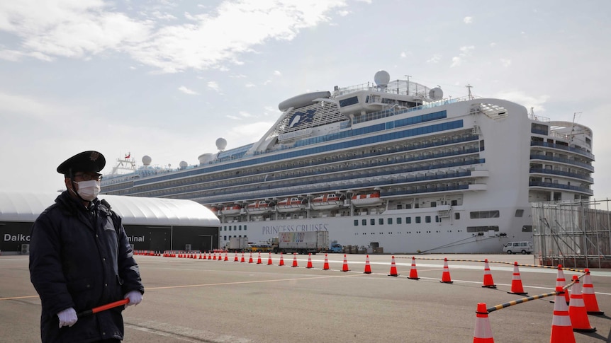 A man in a face mask standing in front of a cruise ship