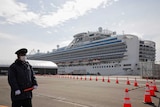 A man in a face mask standing in front of a cruise ship