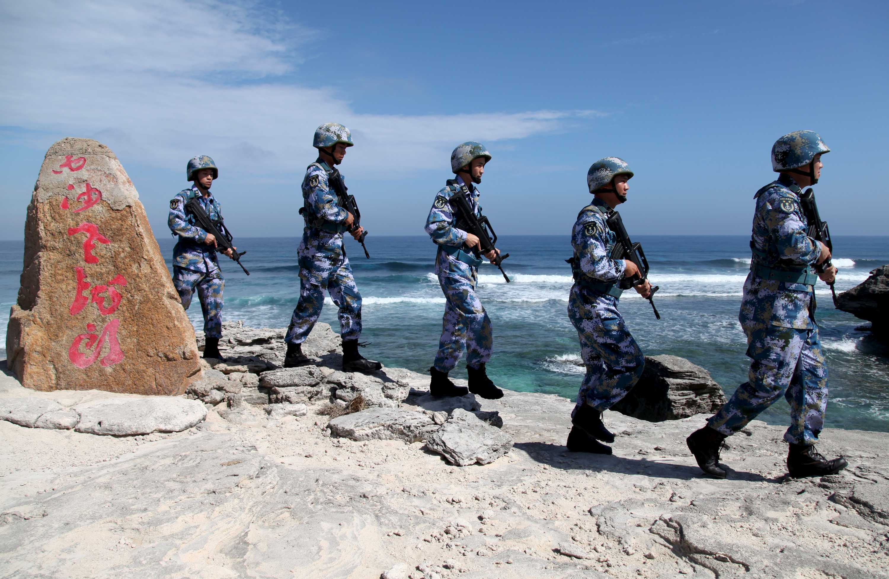 中国人民解放军海军士兵在南中国海的一个岛屿上巡逻时排成一列。
